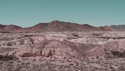 Pastel colors image of a Mojave Desert landscape including badlands and a mountain rage shown near Tecopa in California. Tecopa is located south of Death Valley.
