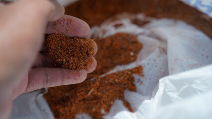 hand grabbing a handful of sawdust from an accumulated sack
