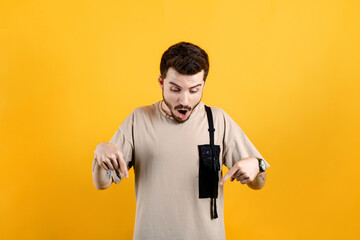 Young man wearing beige t-shirt posing isolated over yellow background surprised and shouting with...
