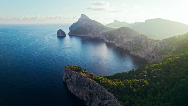 Scenic view of a mountainous region in Majorca with cliffs and green forests. Panoramic view of a sunset over Mirador Es Colomer in Sierra de Tramuntana and blue sea, Balearic Islands, Spain.