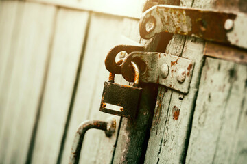 An old rusty padlock closes the wooden old gate on a sunny day. Closed. Safety.
