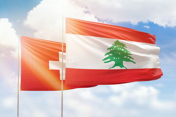 Sunny blue sky and flags of lebanon and switzerland