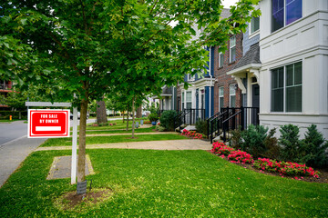 The marketing for sale sign boards of local estate agent Charles Harding outside homes on a street in