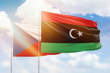 Sunny blue sky and flags of libya and czechia