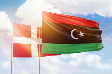 Sunny blue sky and flags of libya and denmark