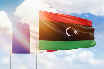 Sunny blue sky and flags of libya and france