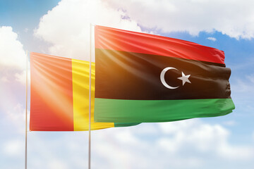 Sunny blue sky and flags of libya and guinea