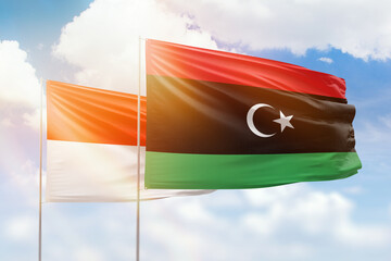 Sunny blue sky and flags of libya and indonesia