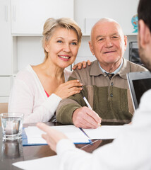 Husband and wife preparing agreement papers in bank with clerk