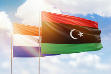 Sunny blue sky and flags of libya and paraguay