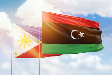 Sunny blue sky and flags of libya and philippines