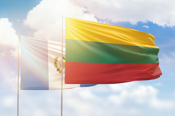 Sunny blue sky and flags of lithuania and guatemala