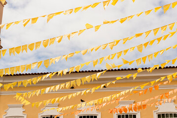 Colorful flags decorating the feast of Sao Joao against blue sky.