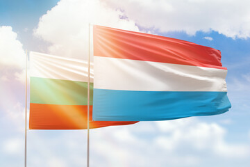 Sunny blue sky and flags of luxembourg and bulgaria