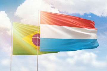 Sunny blue sky and flags of luxembourg and brazil