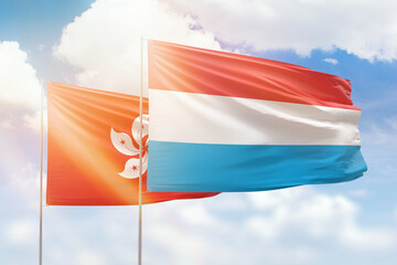 Sunny blue sky and flags of luxembourg and hong kong