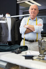 Portrait of an accomplished positive tailor with crossed arms in his workshop