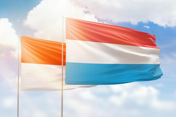 Sunny blue sky and flags of luxembourg and indonesia