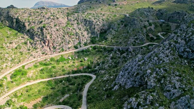Cars, buses and motorcycles drive on European curved road in Majorca, Spain. Nus de Sa Corbata is a spectacular panoramic snake-like road with curves and rocky landscapes by the Mediterranean.