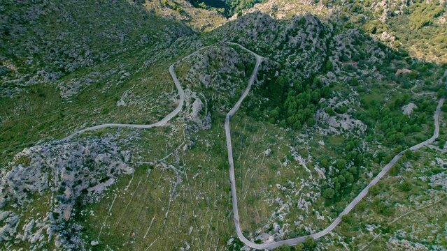 Cars, buses and motorcycles drive on European curved road in Majorca, Spain. Nus de Sa Corbata is a spectacular panoramic snake-like road with curves and rocky landscapes by the Mediterranean.