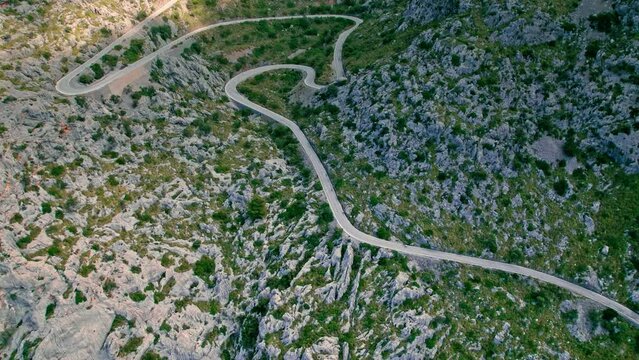 Cars, buses and motorcycles drive on European curved road in Majorca, Spain. Nus de Sa Corbata is a spectacular panoramic snake-like road with curves and rocky landscapes by the Mediterranean.