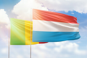 Sunny blue sky and flags of luxembourg and mali