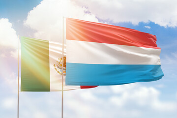 Sunny blue sky and flags of luxembourg and mexico