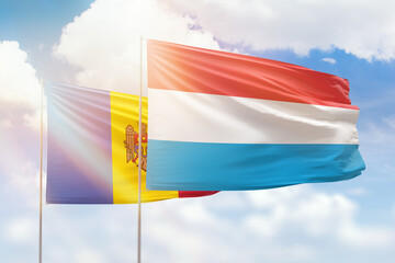 Sunny blue sky and flags of luxembourg and moldova