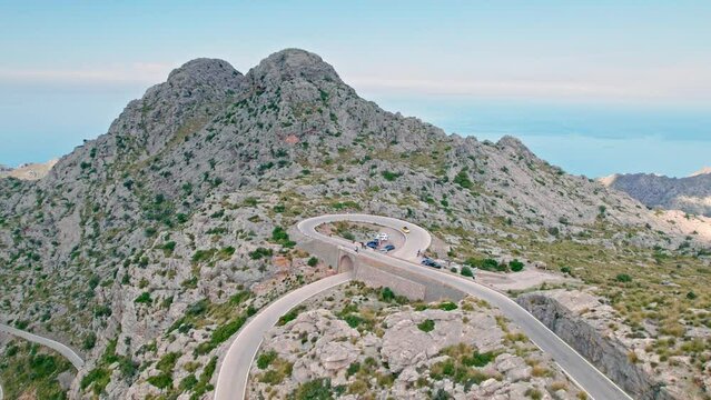 Cars, buses and motorcycles drive on European curved road in Majorca, Spain. Nus de Sa Corbata is a spectacular panoramic snake-like road with curves and rocky landscapes by the Mediterranean.