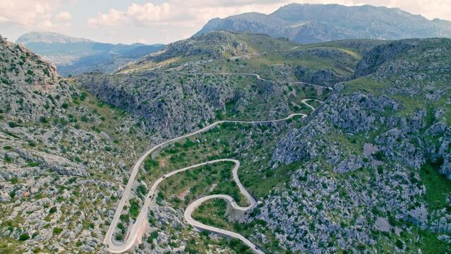 Cars, buses and motorcycles drive on European curved road in Majorca, Spain. Nus de Sa Corbata is a spectacular panoramic snake-like road with curves and rocky landscapes by the Mediterranean.