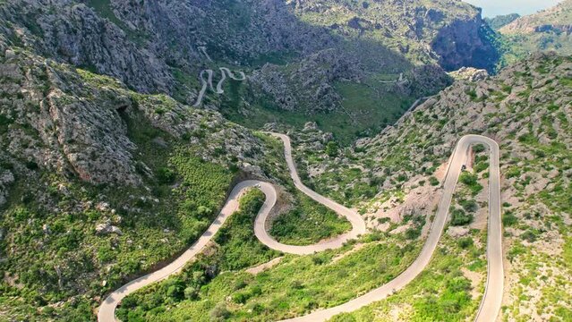 Cars, buses and motorcycles drive on European curved road in Majorca, Spain. Nus de Sa Corbata is a spectacular panoramic snake-like road with curves and rocky landscapes by the Mediterranean.