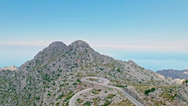 Cars, buses and motorcycles drive on European curved road in Majorca, Spain. Nus de Sa Corbata is a spectacular panoramic snake-like road with curves and rocky landscapes by the Mediterranean.