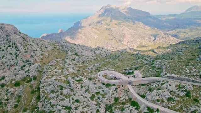 Cars, buses and motorcycles drive on European curved road in Majorca, Spain. Nus de Sa Corbata is a spectacular panoramic snake-like road with curves and rocky landscapes by the Mediterranean.