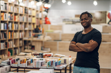 African american man picking and reading books in library or bookstore