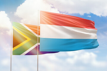 Sunny blue sky and flags of luxembourg and south africa