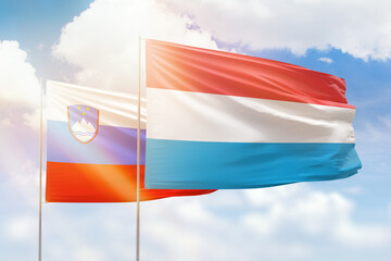Sunny blue sky and flags of luxembourg and slovenia