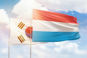 Sunny blue sky and flags of luxembourg and south korea