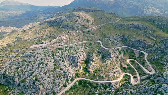 Cars, buses and motorcycles drive on European curved road in Majorca, Spain. Nus de Sa Corbata is a spectacular panoramic snake-like road with curves and rocky landscapes by the Mediterranean.
