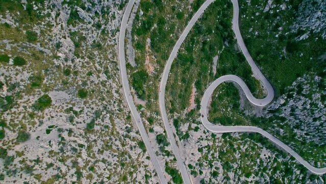 Cars, buses and motorcycles drive on European curved road in Majorca, Spain. Nus de Sa Corbata is a spectacular panoramic snake-like road with curves and rocky landscapes by the Mediterranean.
