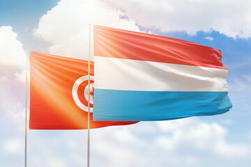 Sunny blue sky and flags of luxembourg and tunisia