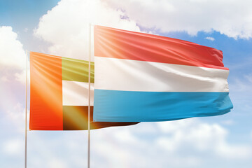 Sunny blue sky and flags of luxembourg and uae