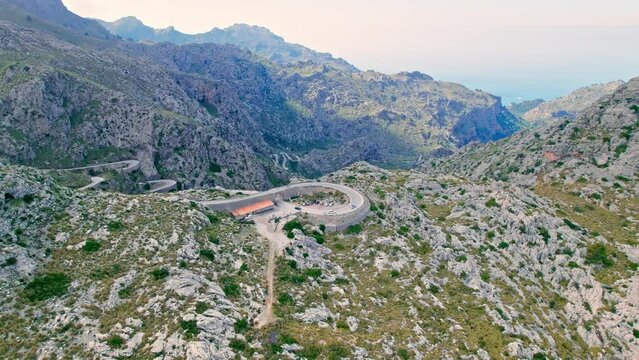 Cars, buses and motorcycles drive on European curved road in Majorca, Spain. Nus de Sa Corbata is a spectacular panoramic snake-like road with curves and rocky landscapes by the Mediterranean.