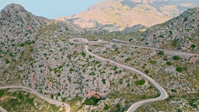Cars, buses and motorcycles drive on European curved road in Majorca, Spain. Nus de Sa Corbata is a spectacular panoramic snake-like road with curves and rocky landscapes by the Mediterranean.
