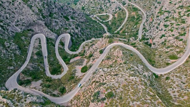 Cars, buses and motorcycles drive on European curved road in Majorca, Spain. Nus de Sa Corbata is a spectacular panoramic snake-like road with curves and rocky landscapes by the Mediterranean.