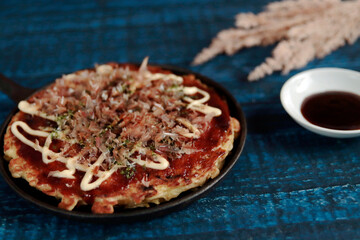 Okonomiyaki in the skillet on the table
