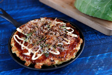 Okonomiyaki in the skillet on the table
