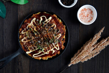 Okonomiyaki in the skillet on the table