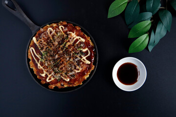 Okonomiyaki in the skillet on the table