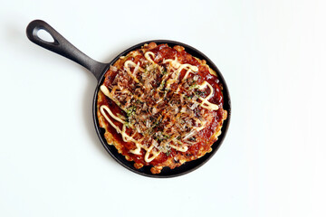 Okonomiyaki in the skillet on the table