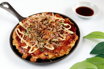 Okonomiyaki in the skillet on the table